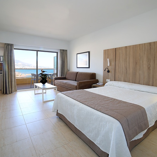 Suite con cama, sofá, cocina y balcón con vistas al mar. PYR Fuengirola