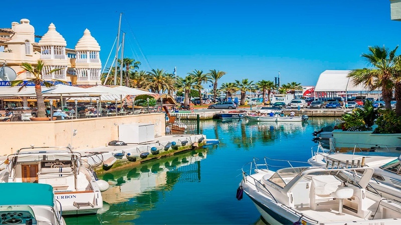 un groupe de bateaux sont amarrés dans un port avec un restaurant en arrière-plan