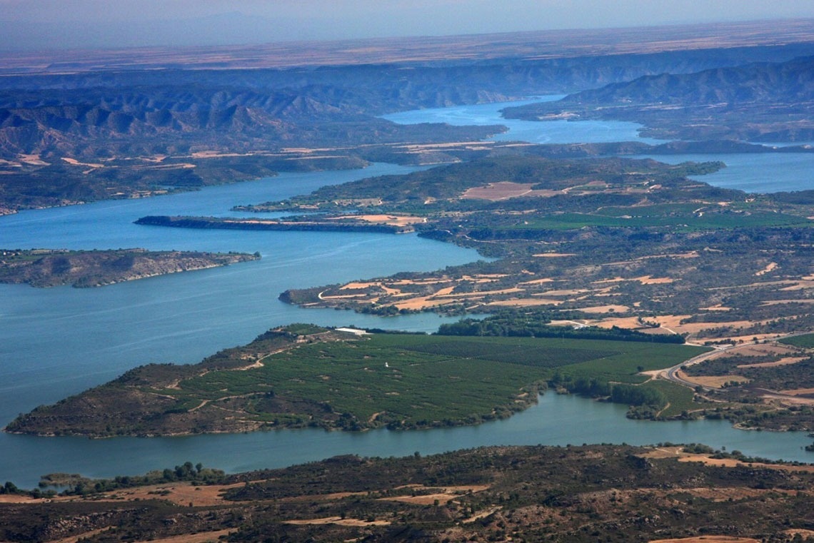 une vue aérienne d' un grand lac avec des montagnes en arrière-plan