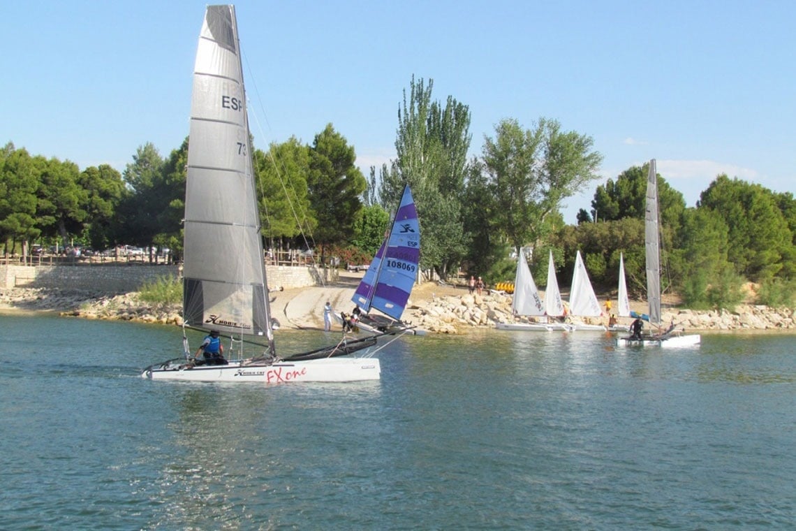 un grup de barcas a vela en un llac i una de les barcas diu rent