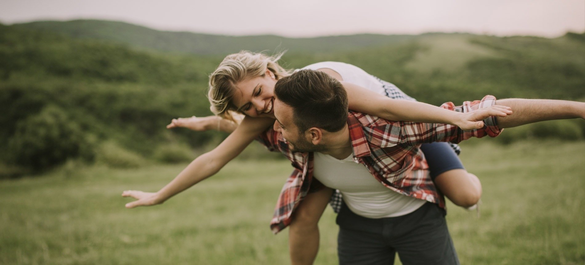 a man is carrying a woman on his back in a field