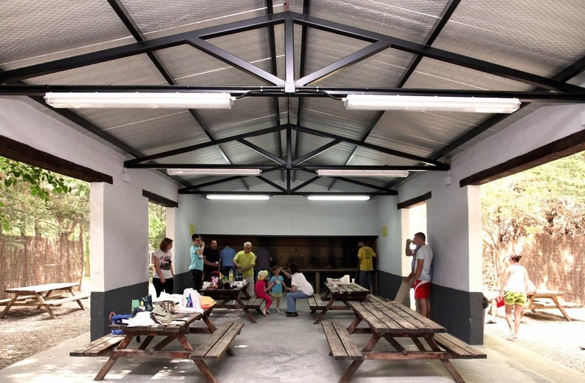 un grupo de personas se reúnen en un cobertizo con mesas de picnic