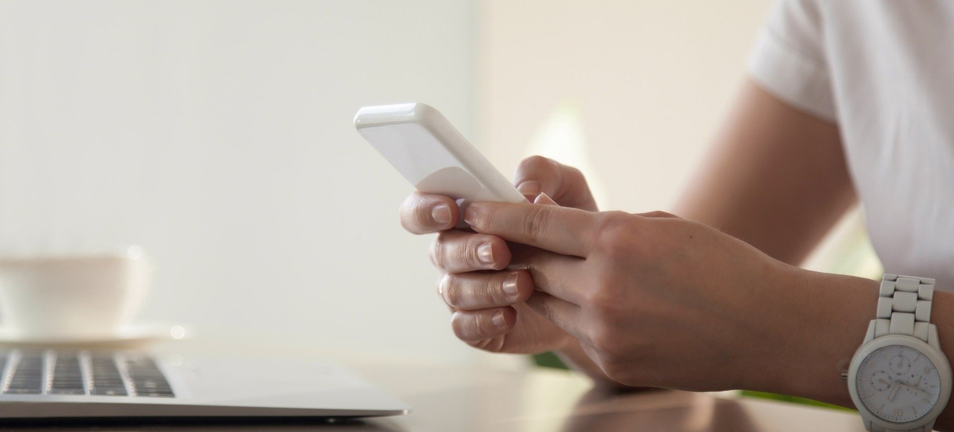 een vrouw houdt een witte mobiele telefoon in haar hand