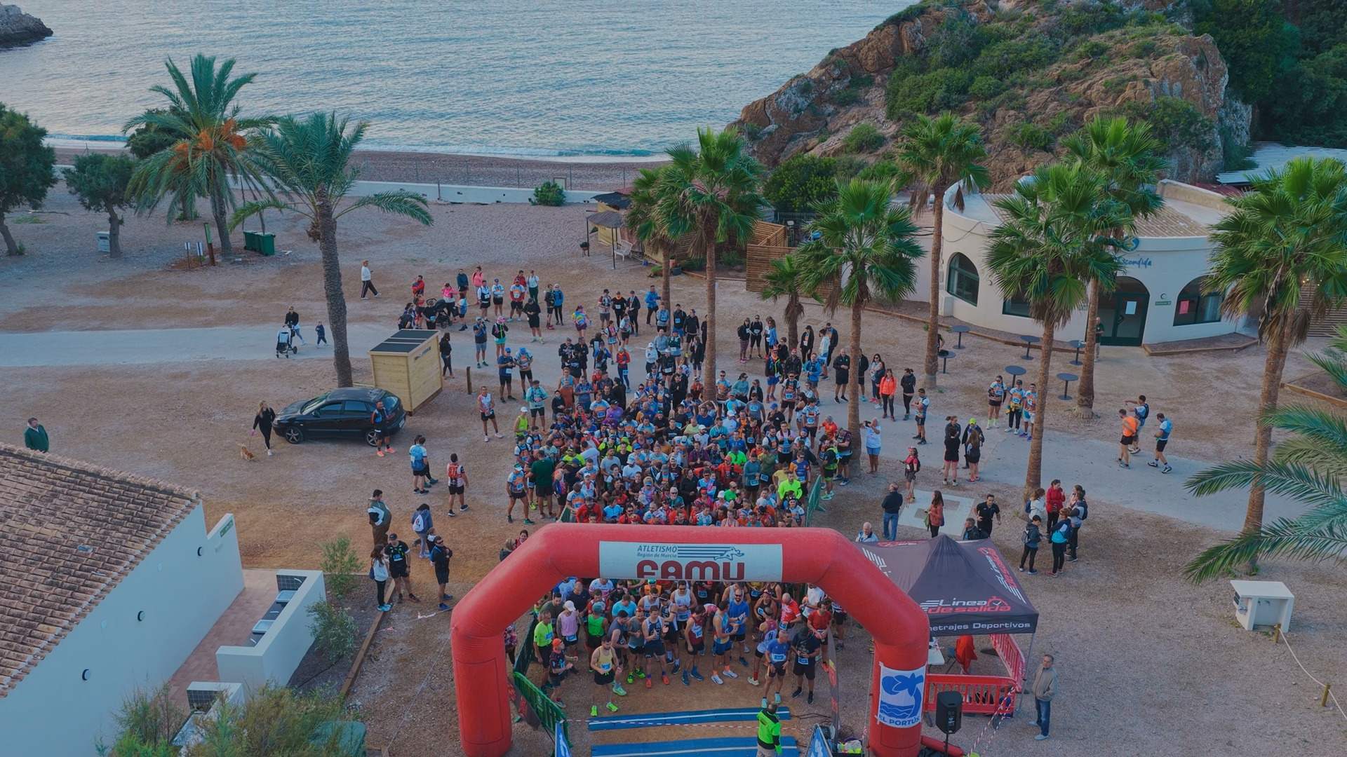Taiga: Corporativa en un evento de carrera en la playa, con participantes y arco de meta.