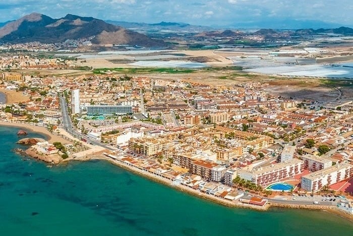 una vista aérea de una ciudad y un océano con montañas en el fondo