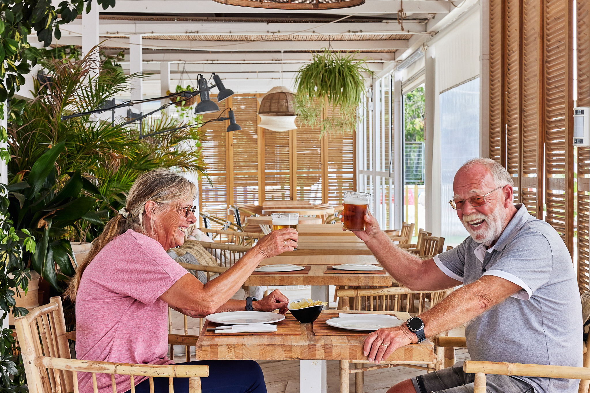 Pareja brindando con cerveza en restaurante de Taiga: Corporativa, estilo tropical.