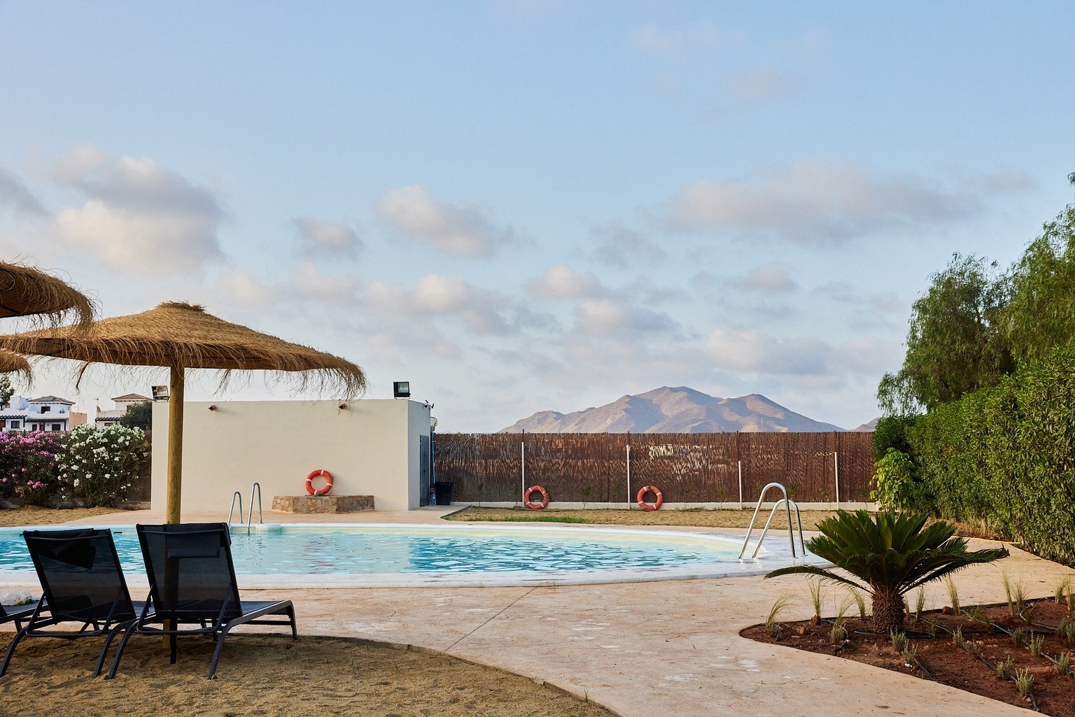 una piscina rodeada de palmeras y un edificio en el fondo