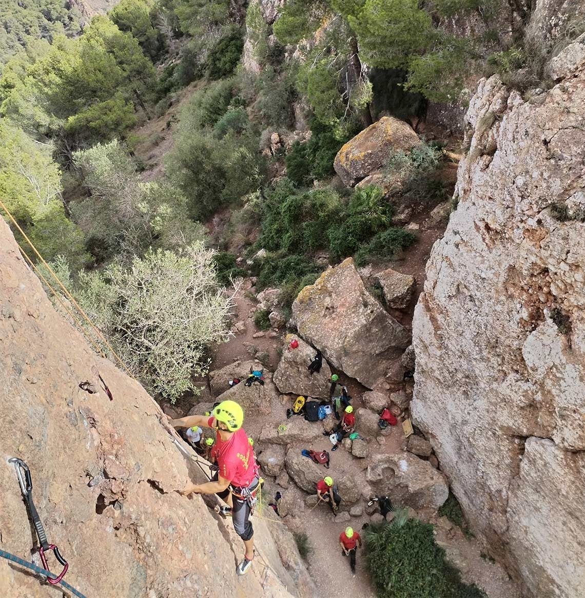 a man wearing a yellow helmet is climbing a rock wall