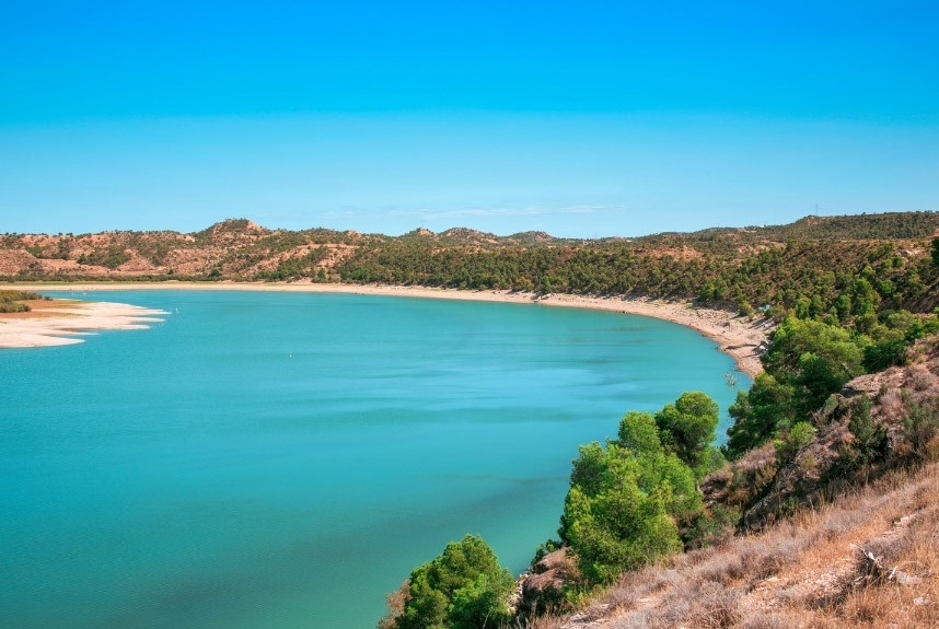 un lago rodeado de montañas y árboles en un día soleado