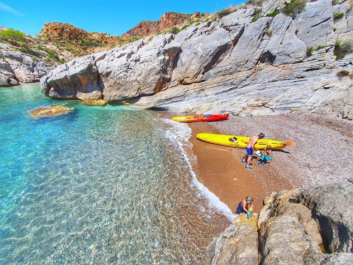 un hombre y dos niños en una playa con kayaks