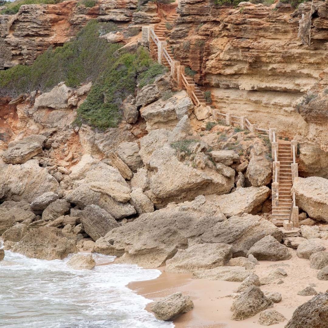 een houten trap leidt naar een rotsachtige klif