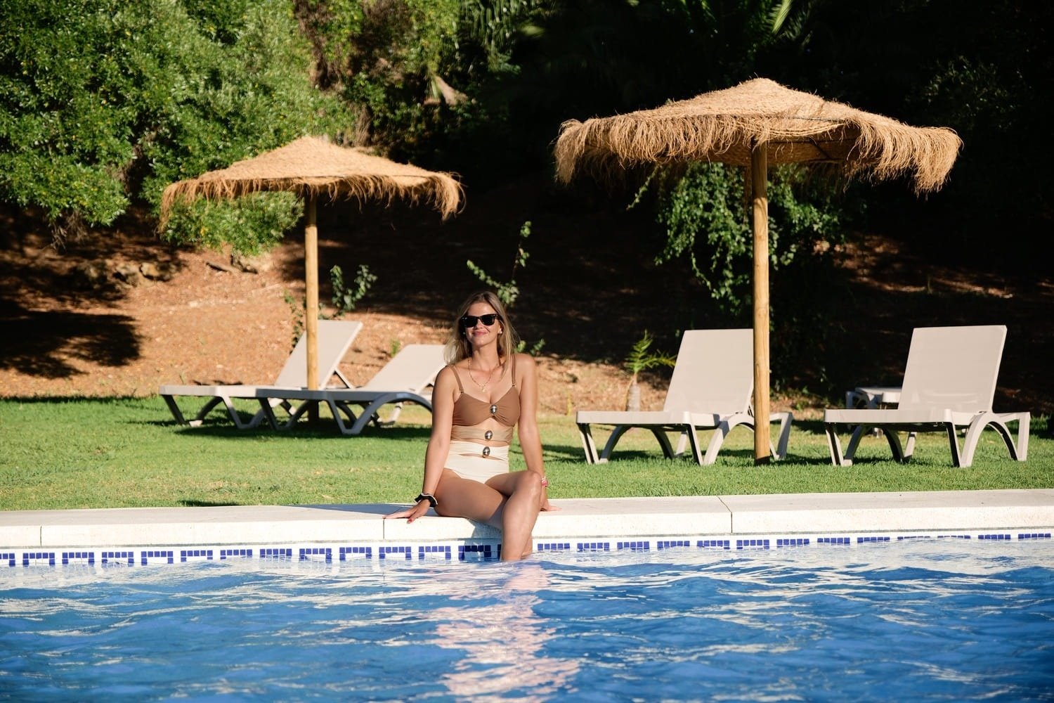 a woman sits on the edge of a swimming pool