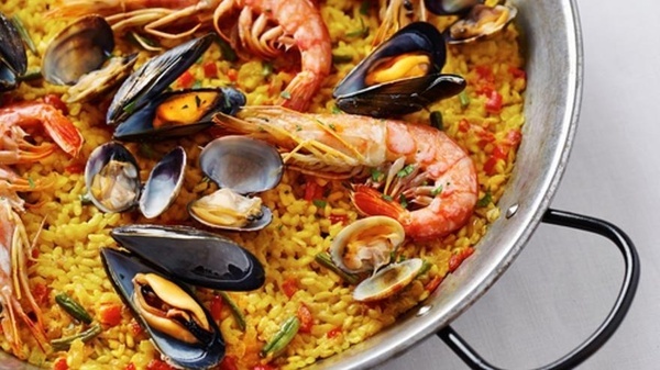 a pan filled with rice and seafood including shrimp mussels and clams