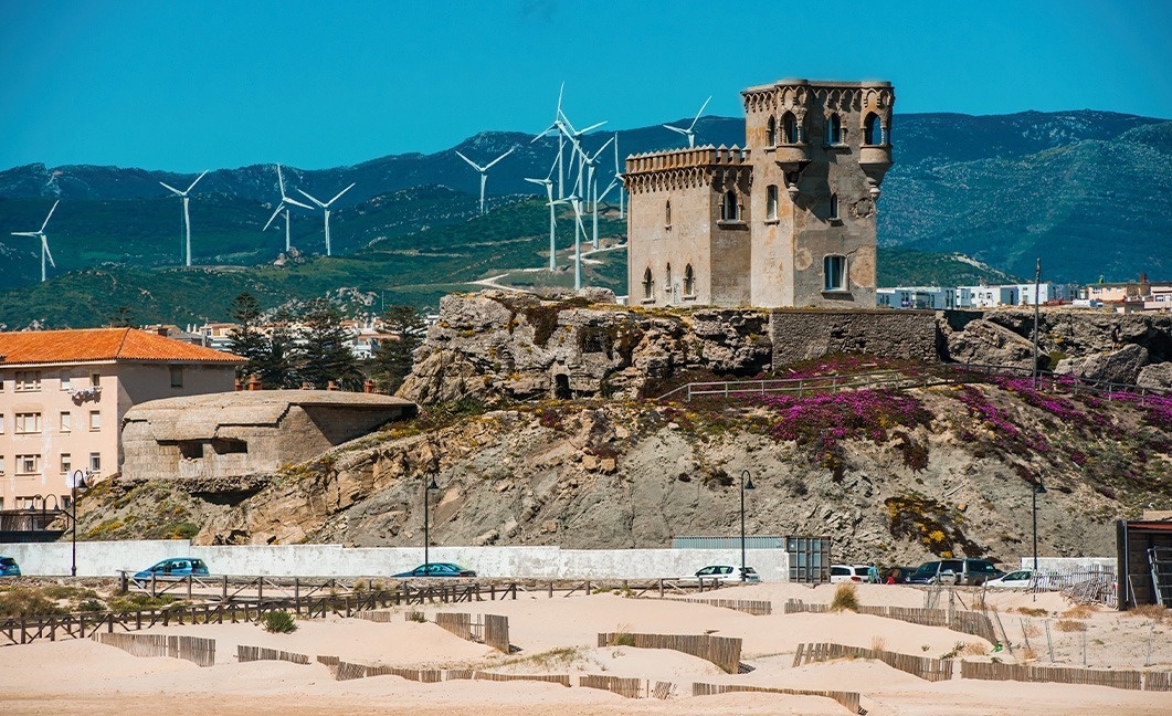 a castle on top of a hill with wind turbines in the background