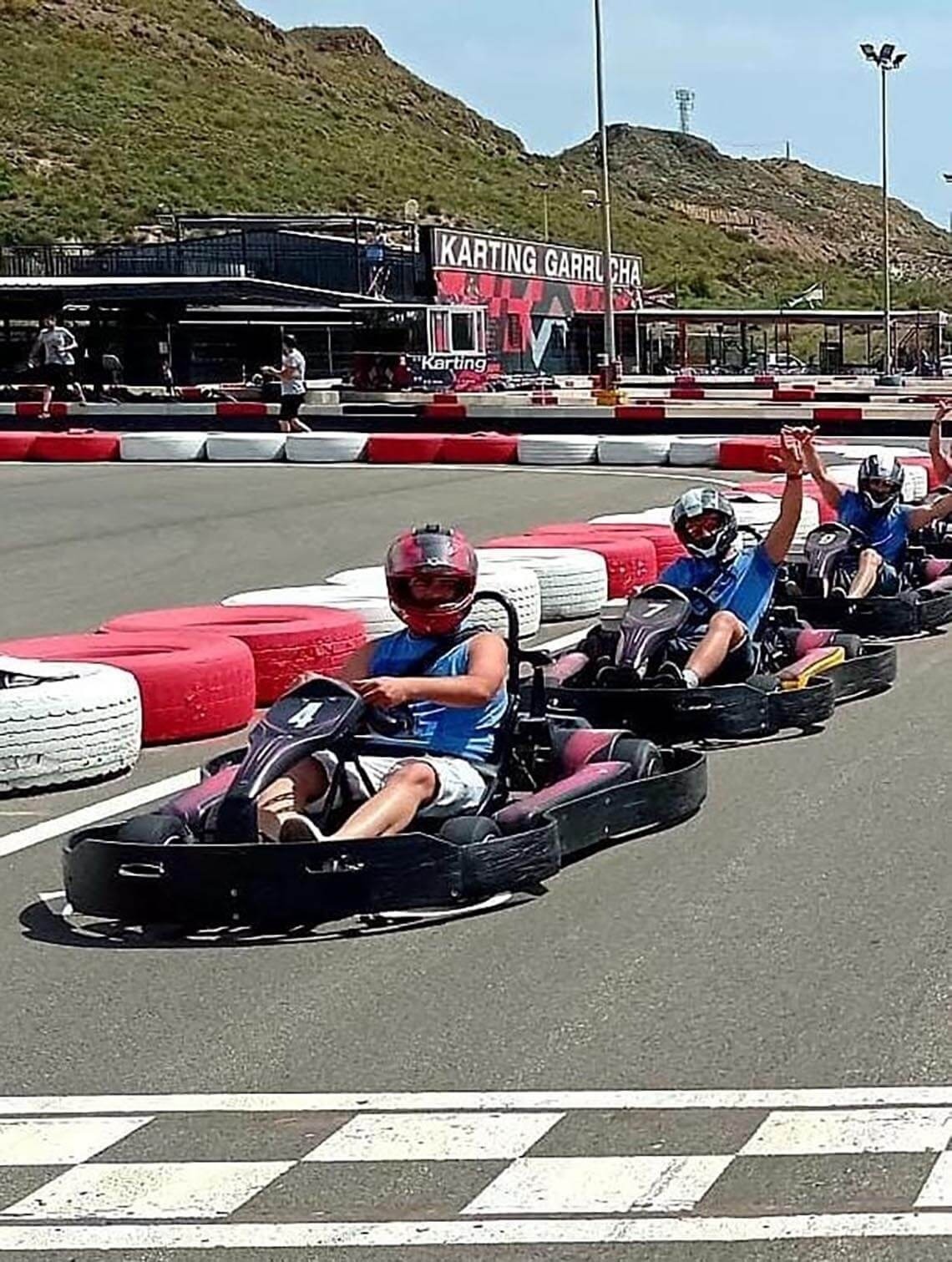 a group of people are riding go karts in front of a building that says karting