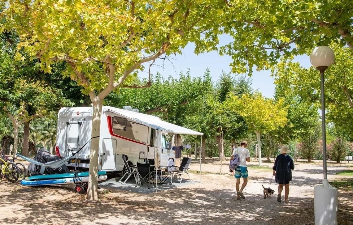 un hombre y una mujer pasean a un perro junto a un remolque .
