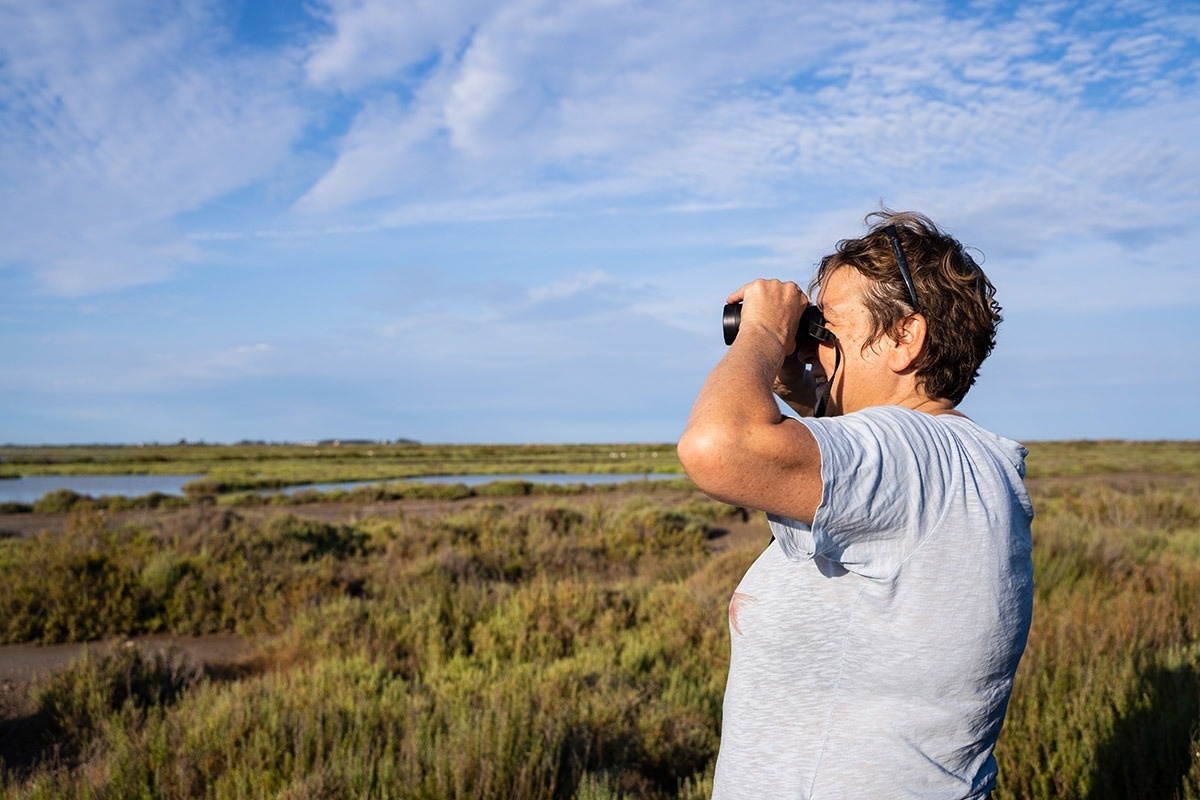 eine Frau schaut durch ein Fernglas in einem Feld