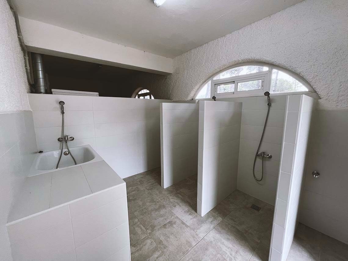 een badkamer met drie douches en een wastafel