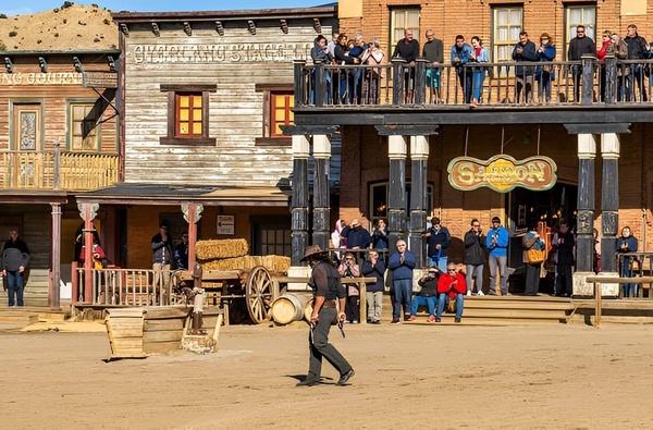 een man die een pistool vasthoudt staat voor een saloon