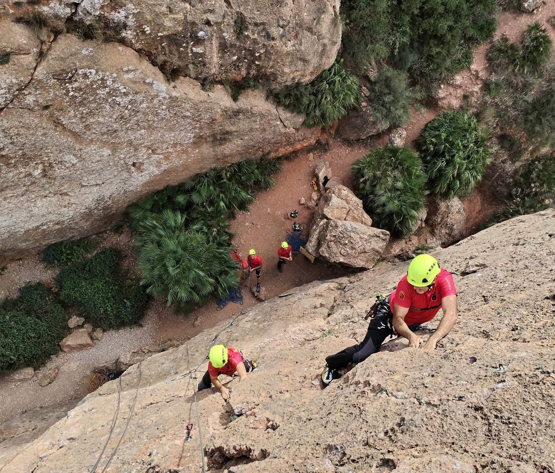 un grup de persones escalant una roca amb cascos i corda