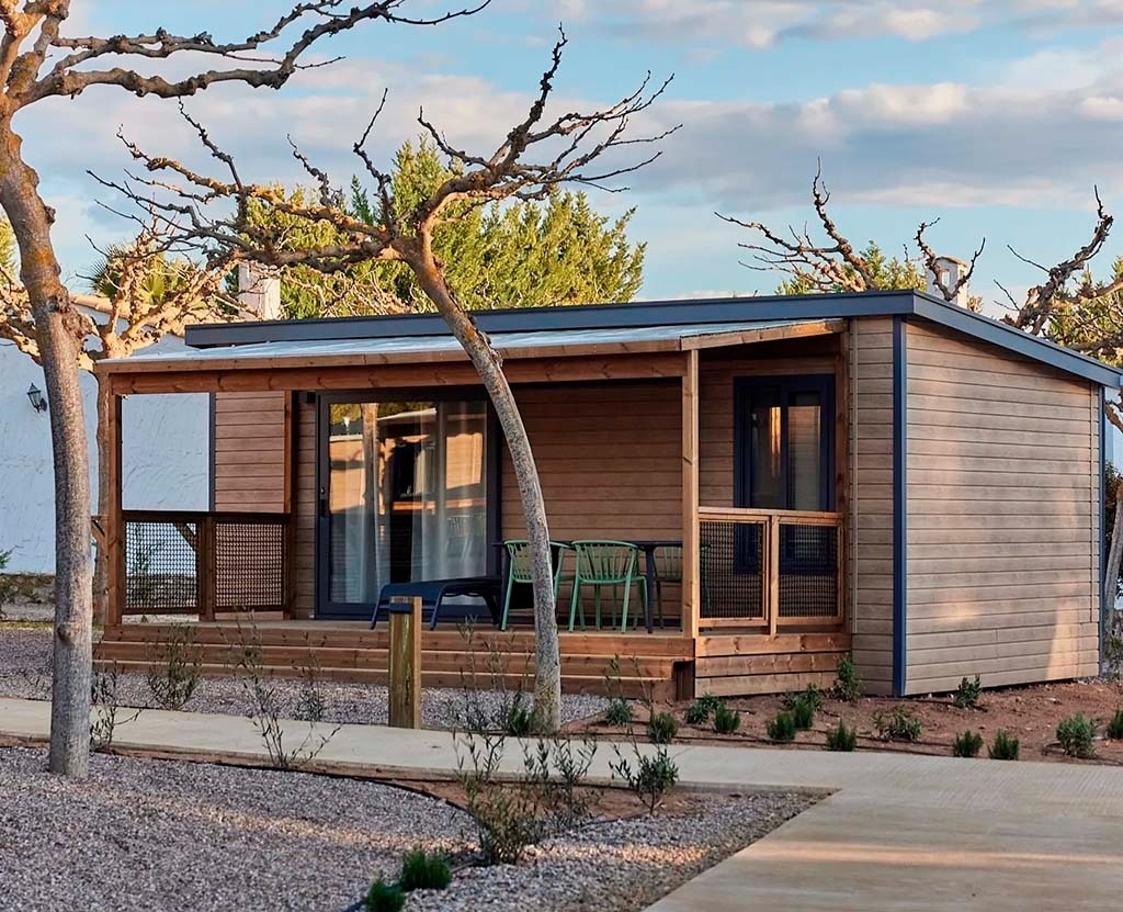 une petite maison en bois avec une table et des chaises sur le porche