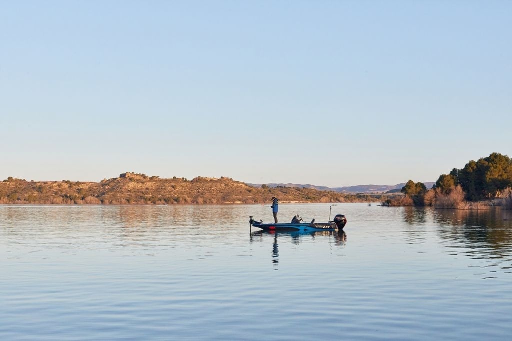 un homme pêche sur un bateau avec une moteur mercury