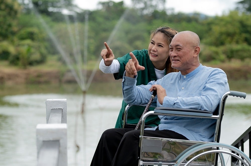 un hombre en silla de ruedas y una enfermera miran una fuente