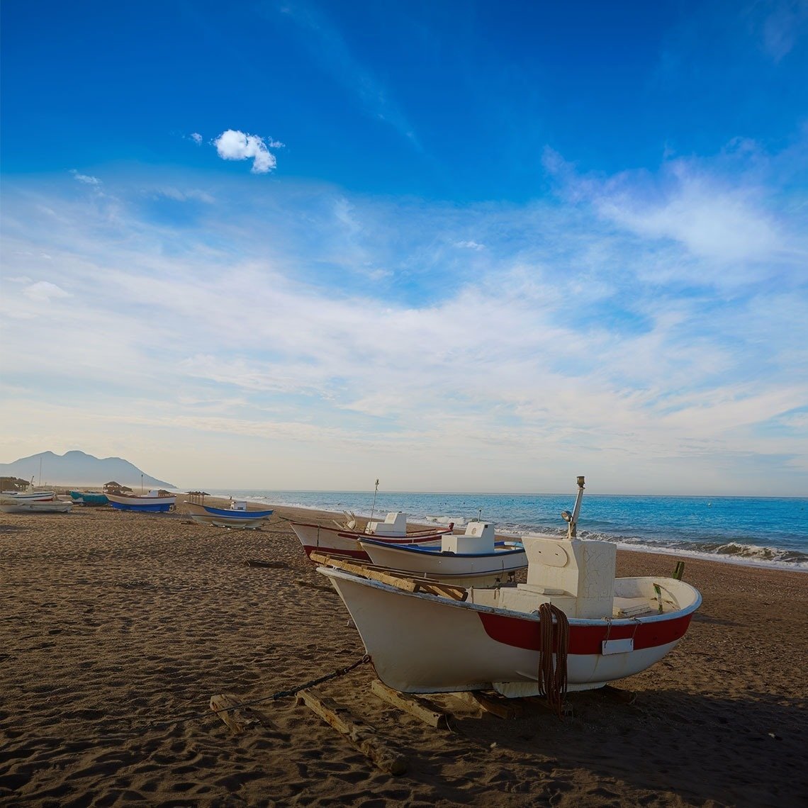 un grup de barques a la platja amb una nuvola en el fons