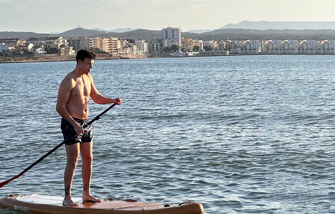 a shirtless man stands on a paddle board that says ' o'neill ' on it