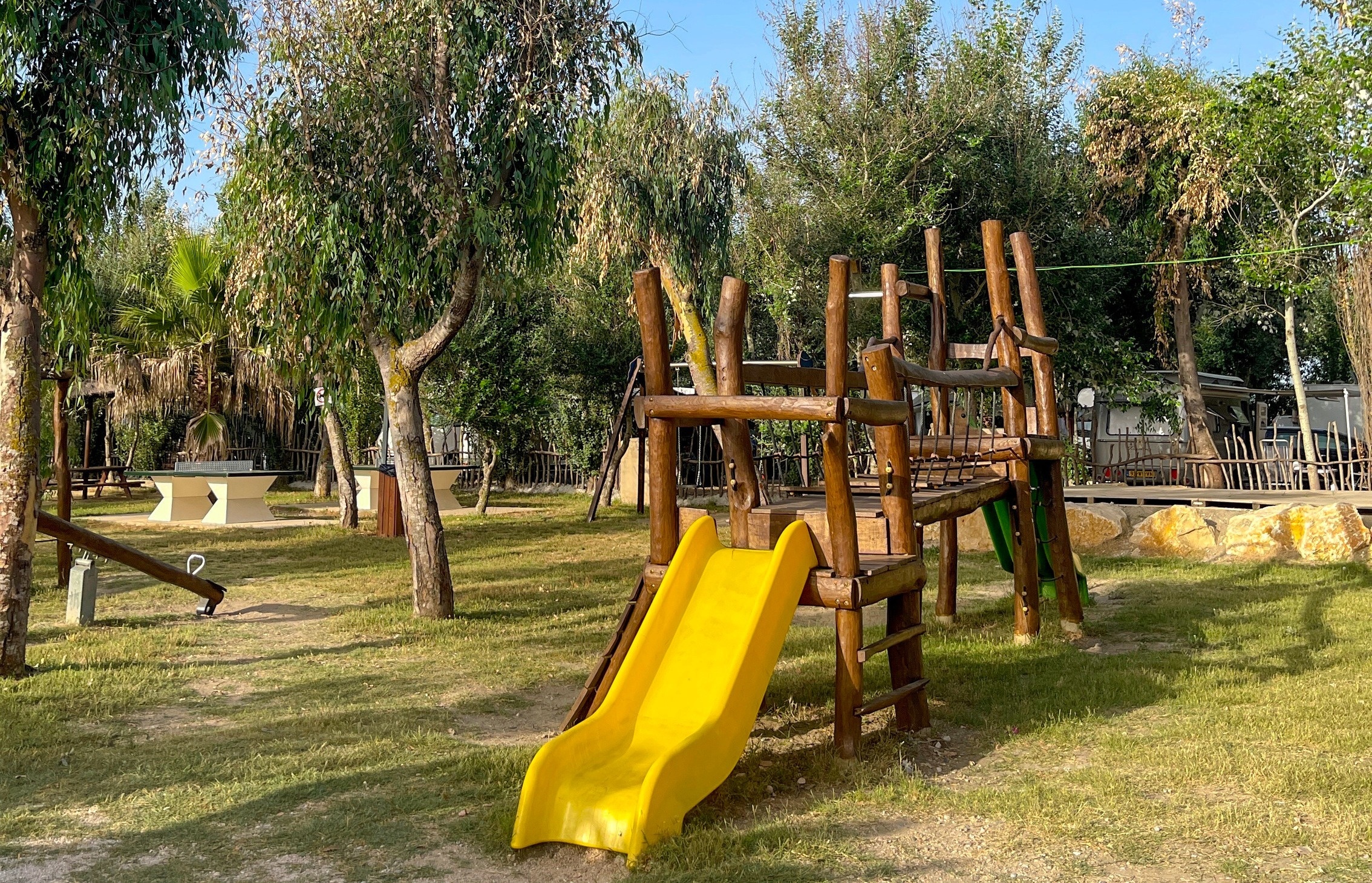 a wooden playground with a yellow slide in the middle