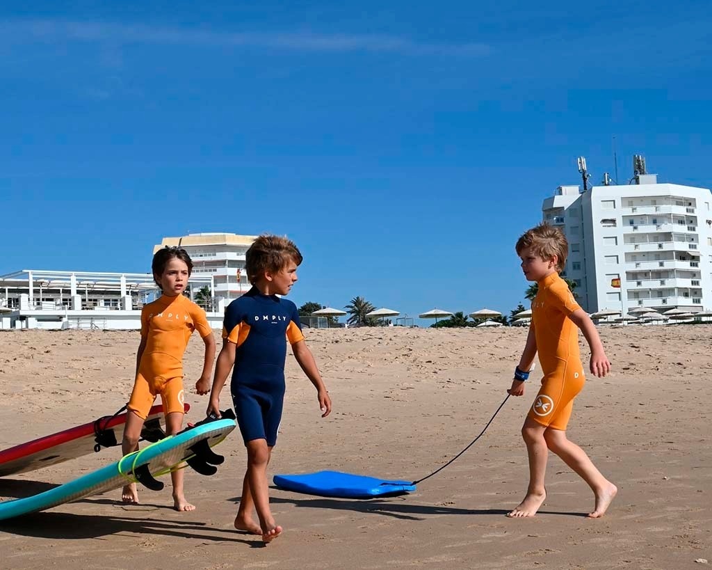 trois jeunes garçons marchent sur la plage portant des wetsuits o'neill