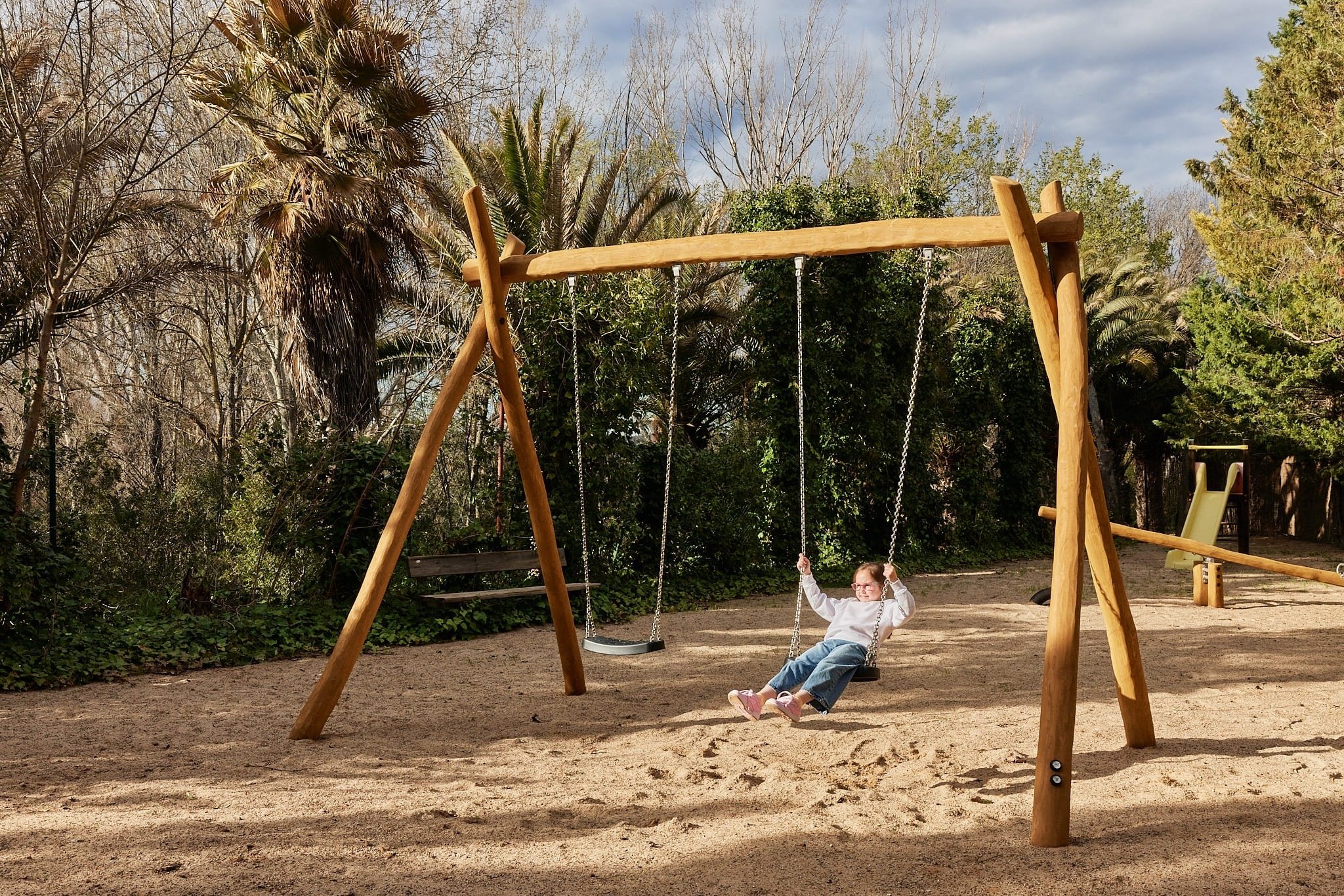 una niña se sienta en un columpio en un parque