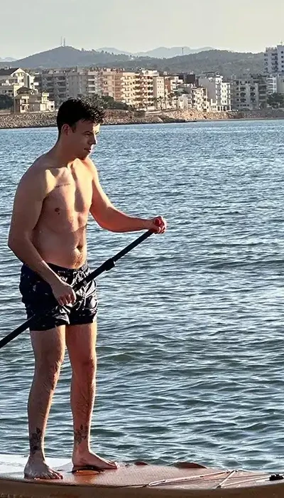 Hombre haciendo paddle surf en el mar, con vistas a la costa TAIGA.
