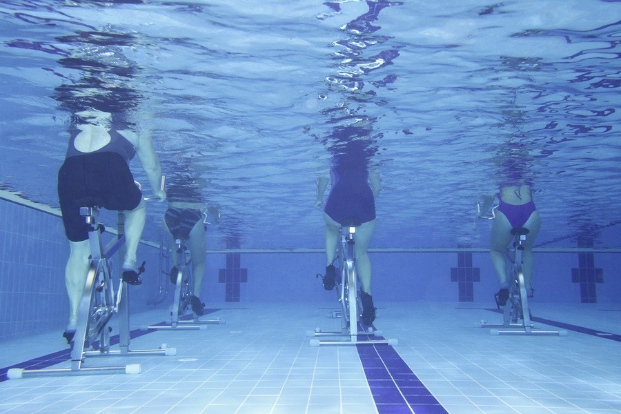 een groep mensen fietst onder water in een zwembad