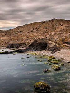 une longue exposition d' une plage avec des rochers et des montagnes en arrière-plan .