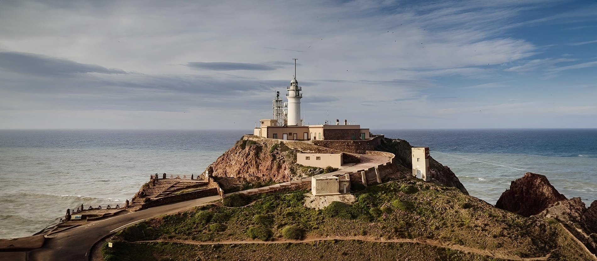 un faro en la cima de una colina con vistas al océano