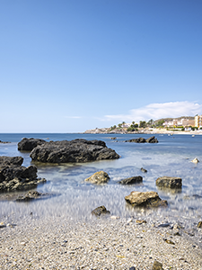 une plage avec des rochers dans l' eau et une ville en arrière-plan