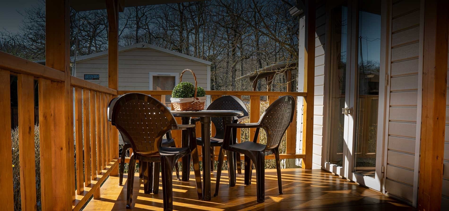 un balcon en bois avec une table et des chaises et un panier de fleurs