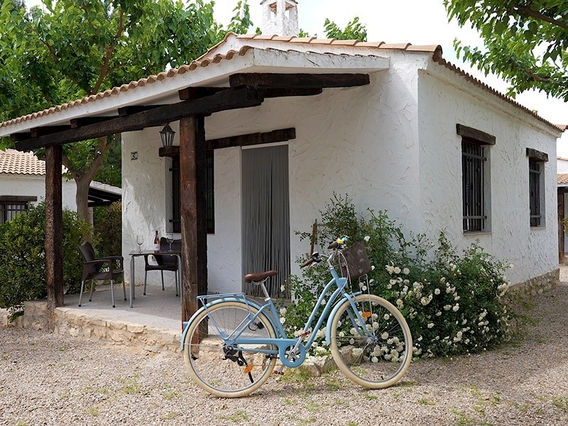 una bicicleta azul está estacionada frente a una pequeña casa blanca