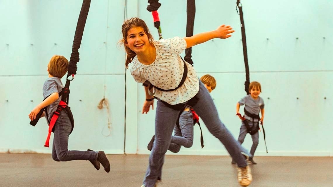 un grupo de niños están saltando en un columpio de bungee