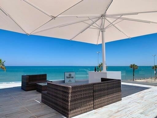 a large umbrella is sitting on top of a patio with a view of the ocean .