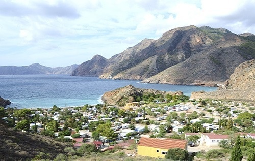 un pequeño pueblo junto a un océano con montañas en el fondo