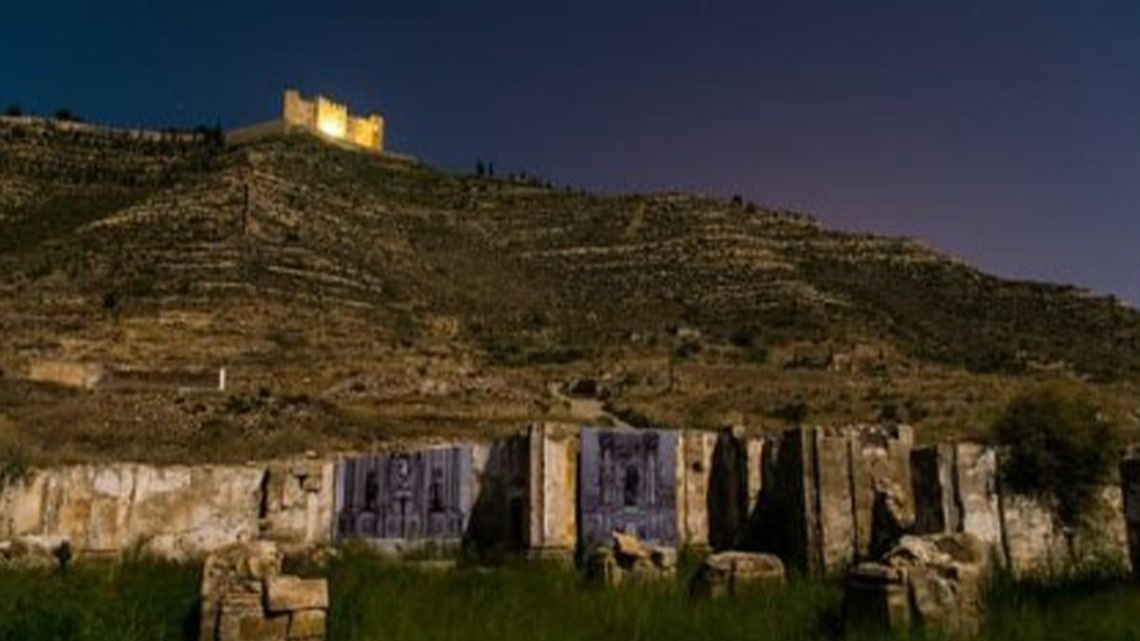 un château est visible au sommet d' une colline la nuit