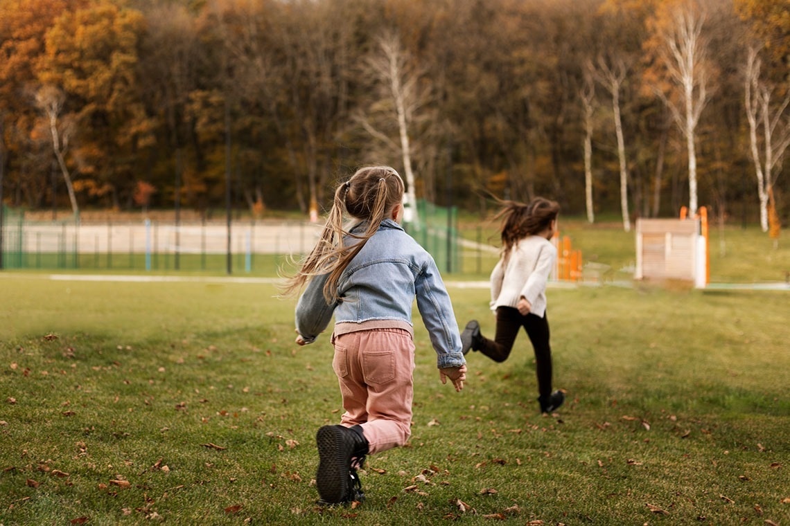 twee meisjes rennen hand in hand over een grasveld