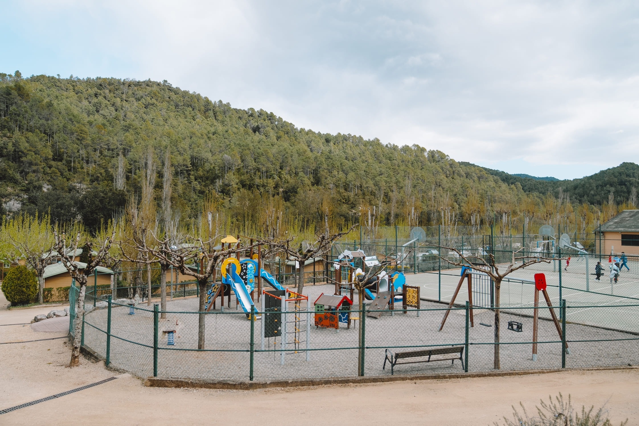 Parque infantil y cancha polideportiva en hotel, con cabañas y naturaleza.