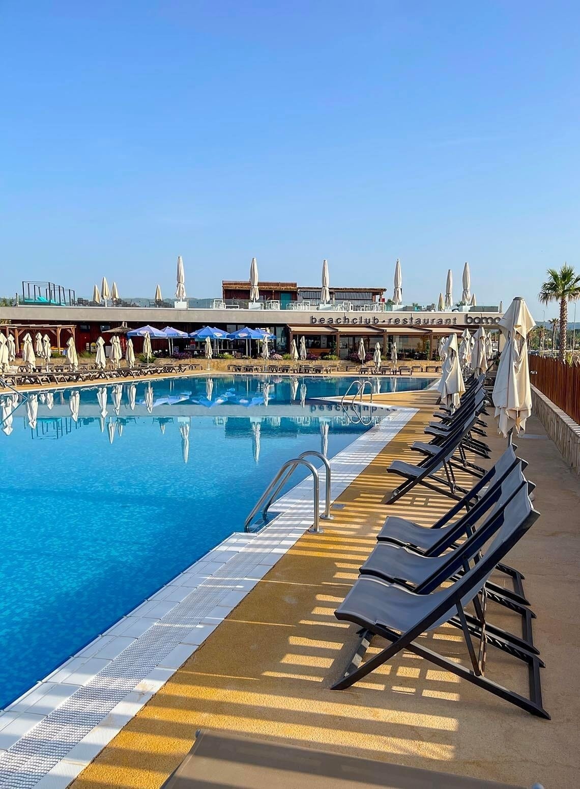 a large swimming pool surrounded by chairs and umbrellas