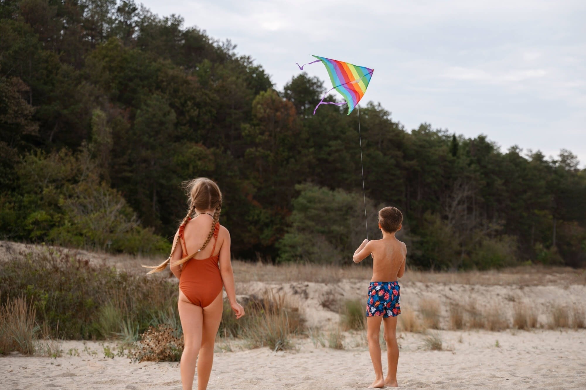 un niño y una niña volan un cometa en la playa