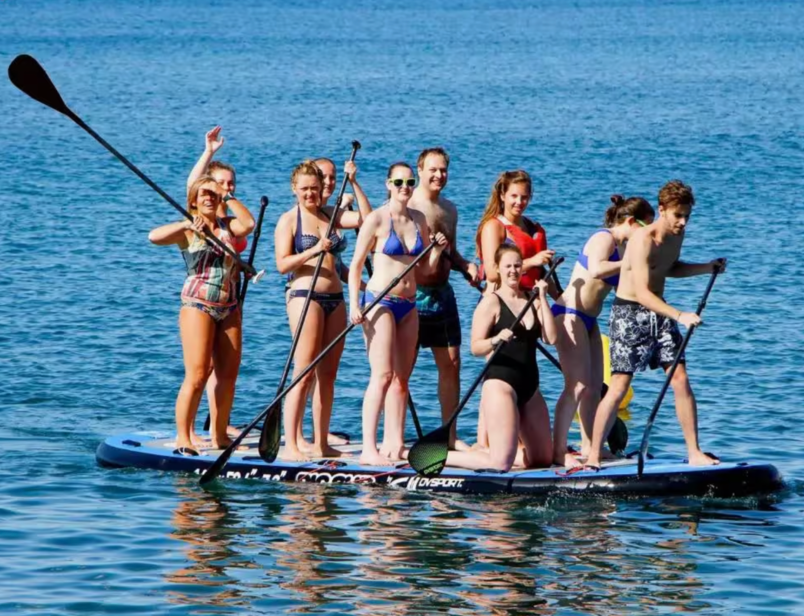 un grup de persones a l' aigua amb paddle boards amb la imatge de l' esport