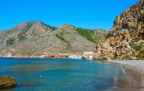 una escalera de madera conduce a una playa a lo largo de un acantilado rocoso