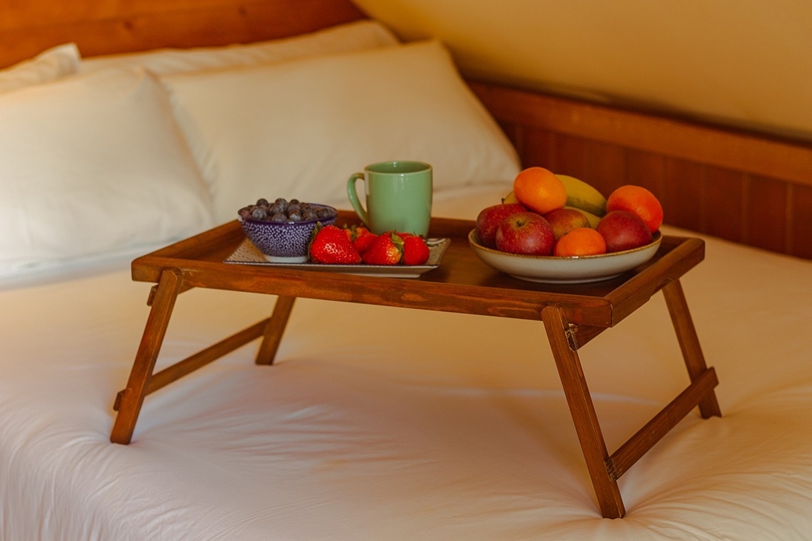 a wooden tray with fruit and a cup on it